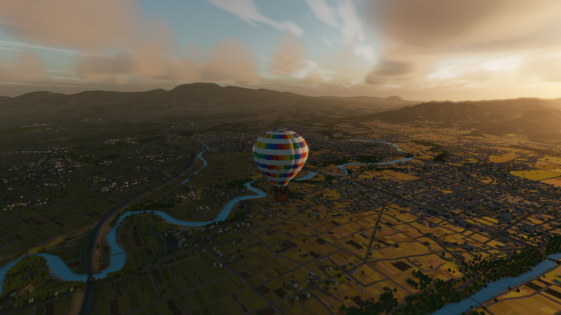 A balloon drifting over fields and a river at sunrise